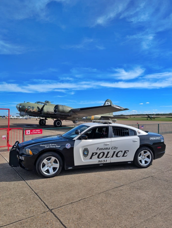 Our black-and-white Panama City Police Dodge Charger beside a vintage aircraft, before joining Booked and Charged.